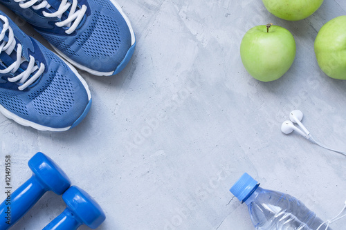 Flat lay sport shoes, dumbbells, earphones, apples, bottle of wa
