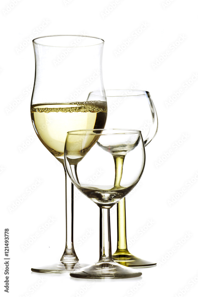 three drinking glasses, one is filled with white wine, the other are empty, isolated on white