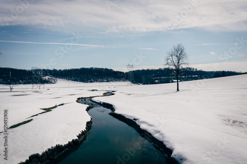 Small stream through a snow covered farm field in rural Carroll