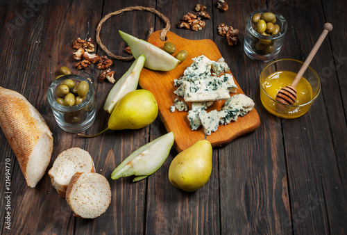 Blue cheese with honey, olive and pears on rustic table