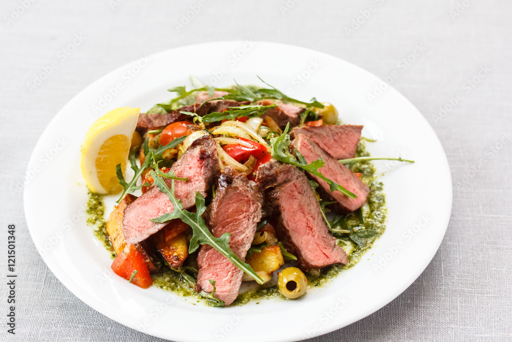 Roast beef with arugula, vegetables and lemon sliced, lies on th Roast beef with arugula, vegetables and lemon sliced, lies on th