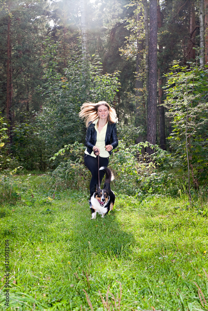 Young woman and dog Cardigan Welsh Corgi running in the park