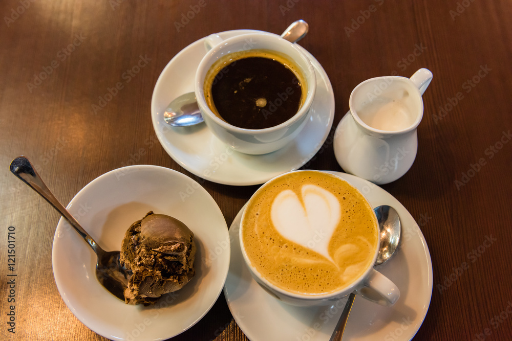Cup of black coffee, cup of cappuccino and a milk jug Cup of black coffee, cup of cappuccino and a milk jug