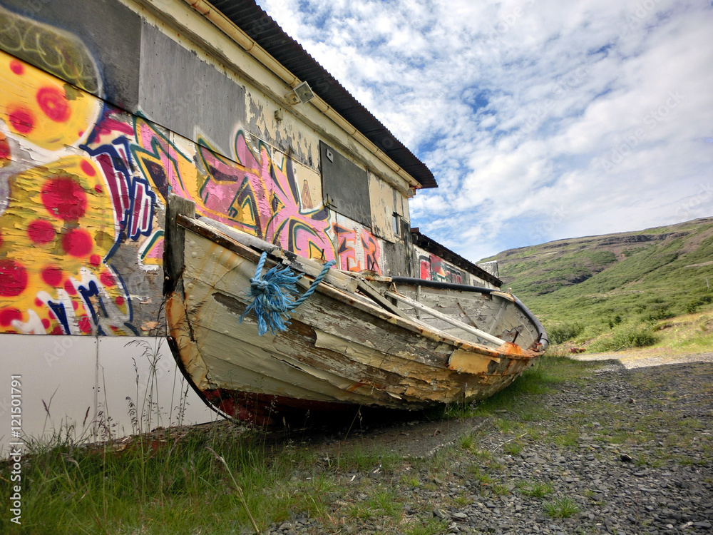 Wooden boat abandoned in urban setting with graffiti