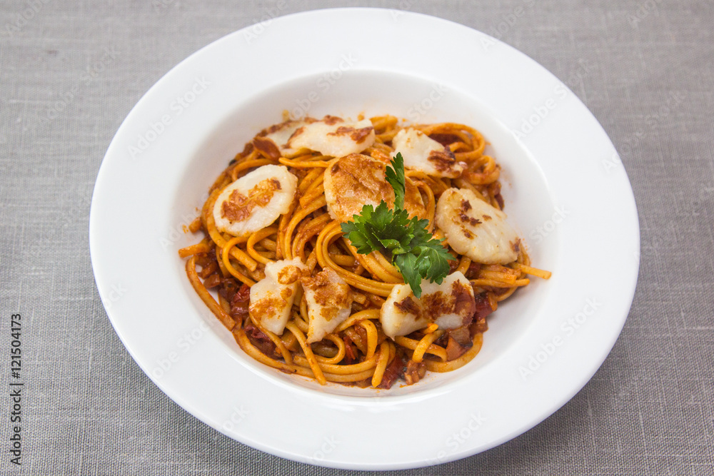 Pasta (spaghetti) with scallops and tomato sauce is on the plate Pasta (spaghetti) with scallops and tomato sauce is on the plate