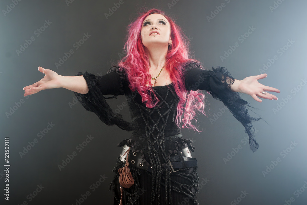 Halloween Witch creates magic. Attractive woman with red hair in witches costume standing outstretched arms, strong wind Halloween Witch creates magic. Attractive woman with red hair in witches costume standing outstretched arms, strong wind