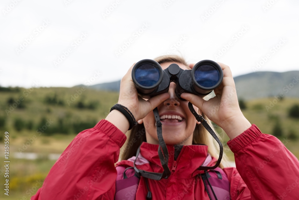 young blonde woman hiking and watching through binoculars. young blonde woman hiking and watching through binoculars.