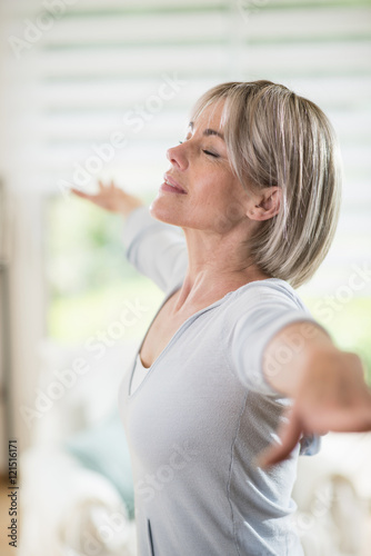 a 50 year old  woman who does yoga, eyes closed in her house © jackfrog