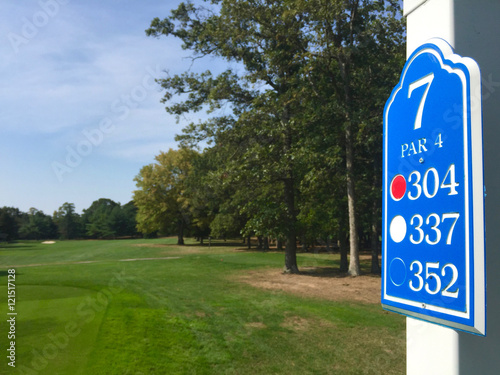 Public golf course hole number sign - Display distance to green from tee box markers for player to judge how far they will need to drive the ball down the fairway. Decision for type of club to use.
