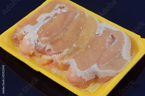 Fotografija Frozen chicken breast tenderloin meat lightly covered with ice thawing in packag