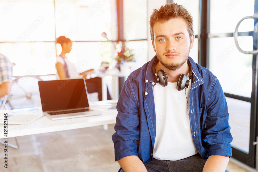 Young man sitting and looking at camera in office