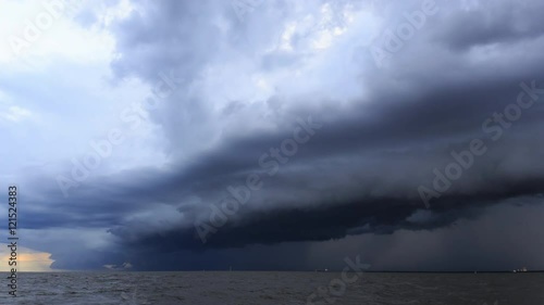 4K Time Lapse : Rain clouds spread across the sky before sunset at sea, estuary, with Cargo ships sail past.
