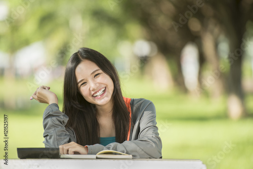 Teenage girl enjoying reading on a blanket at the park