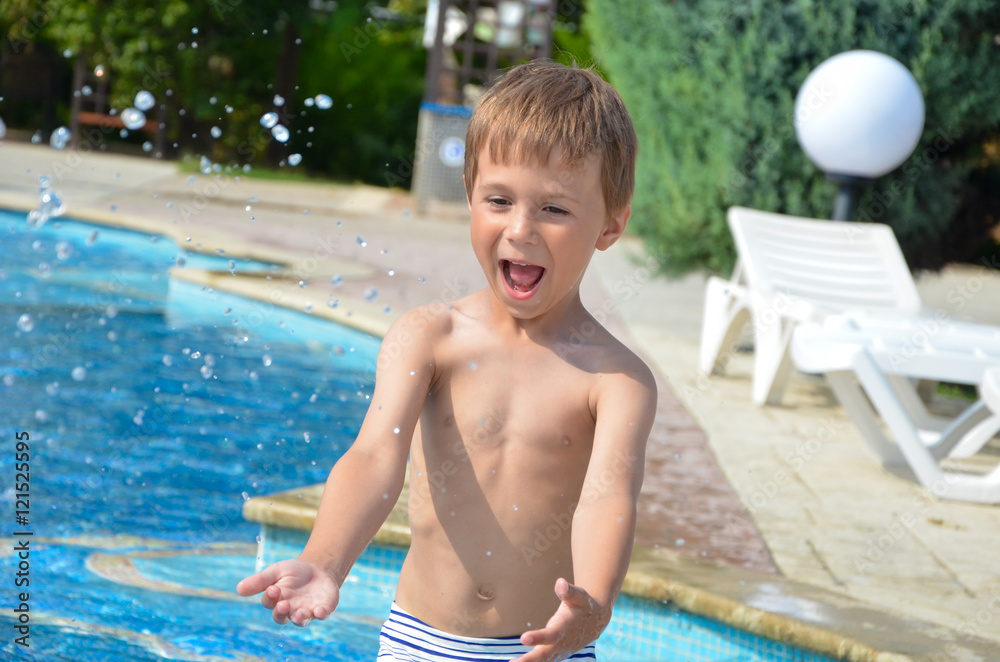 Мальчик в бассейне с брызгами воды
