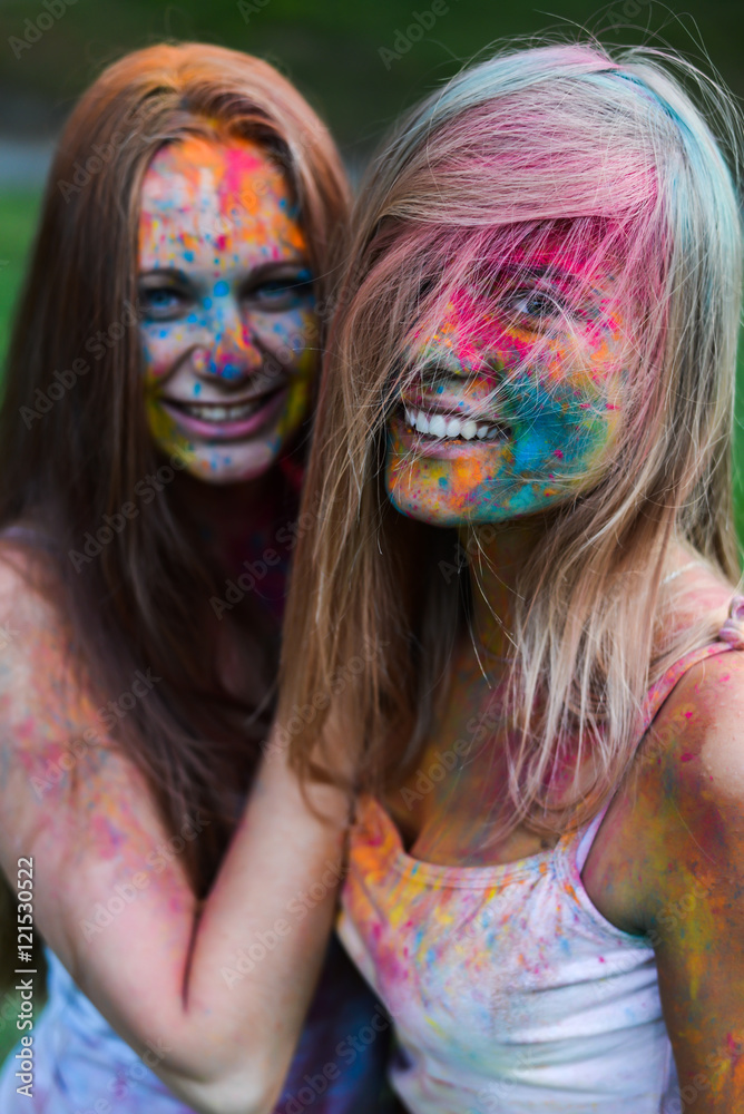 Obraz premium girls celebrate Indian holi festival with colorful paint powder on faces and body