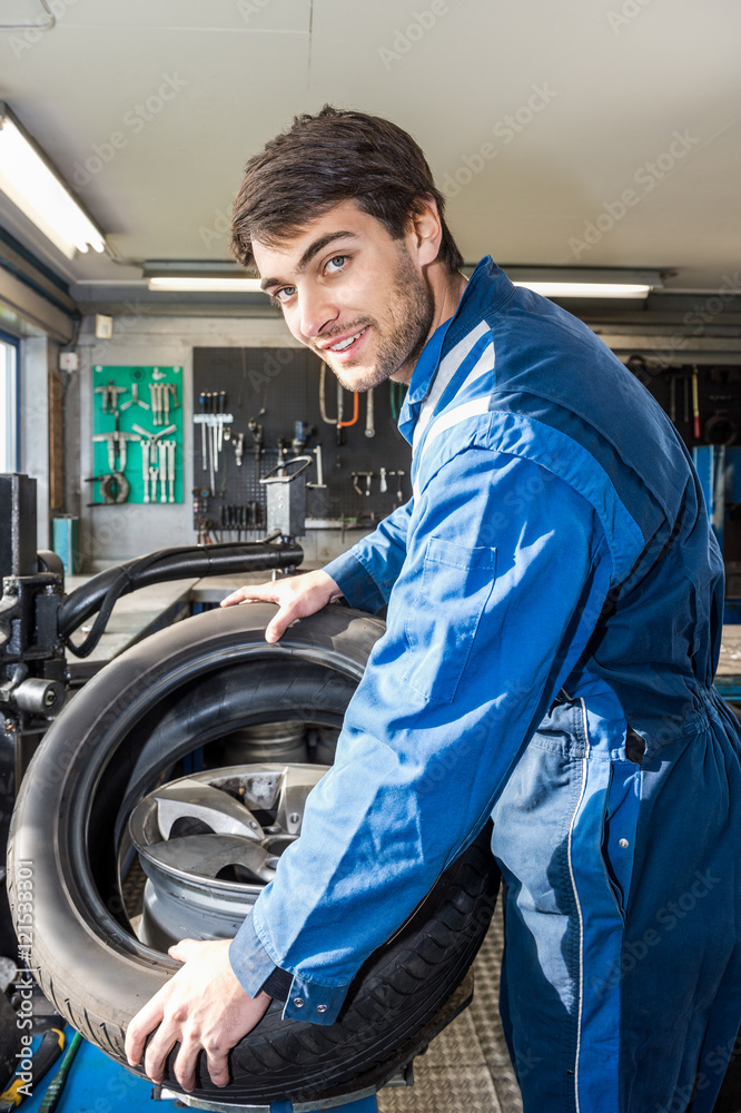 Confident Mechanic Mounting Car Tire On Rim In Garage Confident Mechanic Mounting Car Tire On Rim In Garage