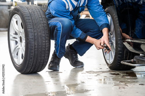 Male Mechanic Changing Car Tire In Garage photo