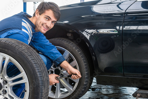 Confident Mechanic Changing Car Tire At Automobile Shop © corepics