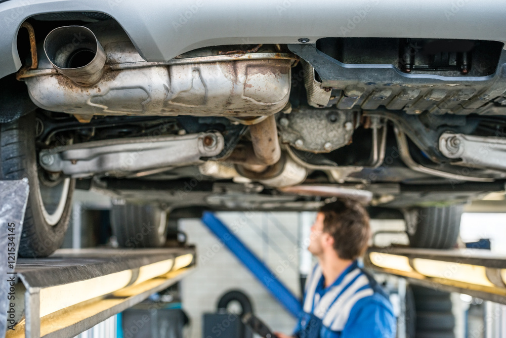 Car On Hydraulic Lift With Mechanic Working In Garage Car On Hydraulic Lift With Mechanic Working In Garage
