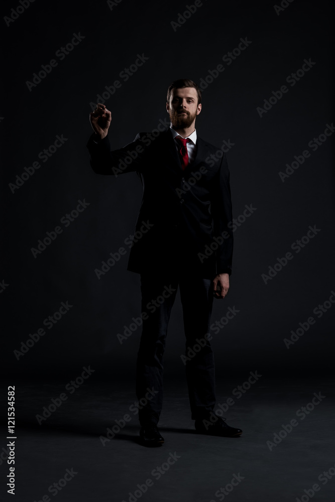 Businessman writing imaginary text on a dark background Businessman writing imaginary text on a dark background