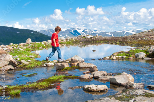 Child crossing mountain lake in Norway