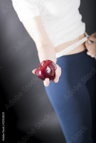 Doctor measuring woman with measuring tape a girl who has an apple in his hand