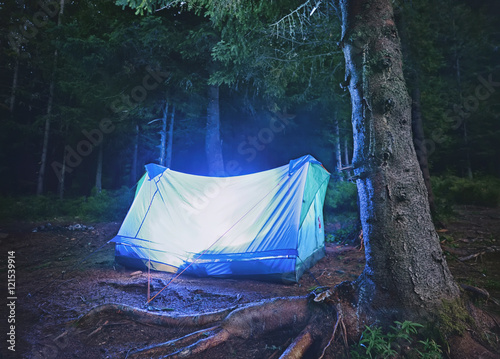 Illuminated blue tent at night forest , Carpathian ,Ukraine