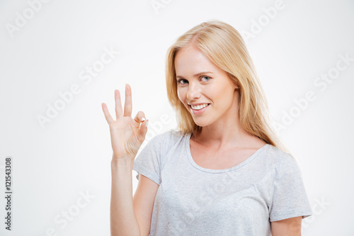 Smiling blonde woman showing ok sign isolated
