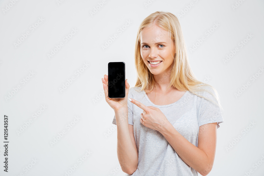 Smiling young woman pointing finger at blank smartphone screen Smiling young woman pointing finger at blank smartphone screen