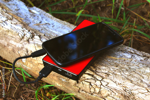 Foto Powerbank and smartphone on a log