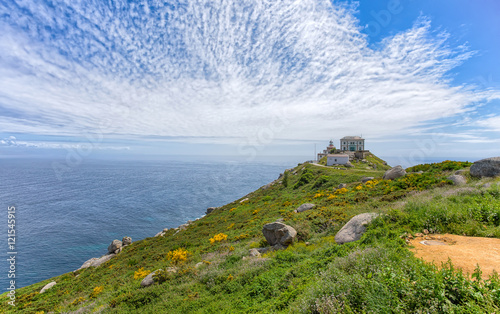 View of Cape Finisterre, Galicia, Spain with the lighthouse under a cloudy blue sky photo