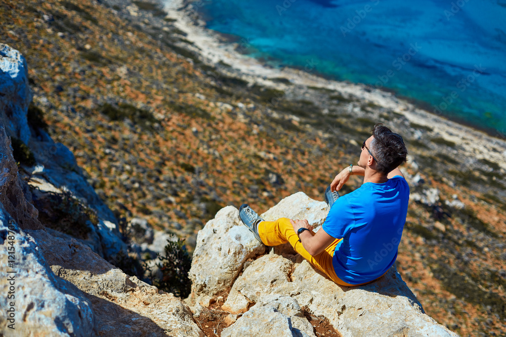 male traveler on the cliff against blue sky and sea
