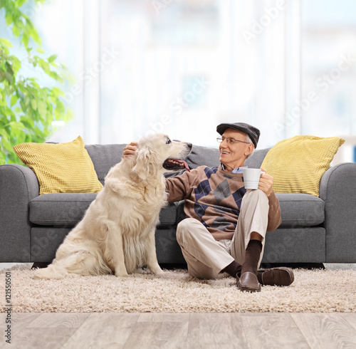 Elderly man sitting on the floor and petting his dog