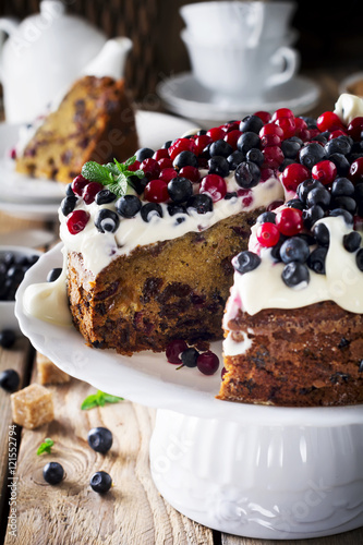 Cake with fresh berries and cream on old wooden background. Selective focus.