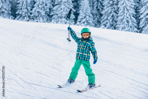 Little skier cheering, holding ski poles up