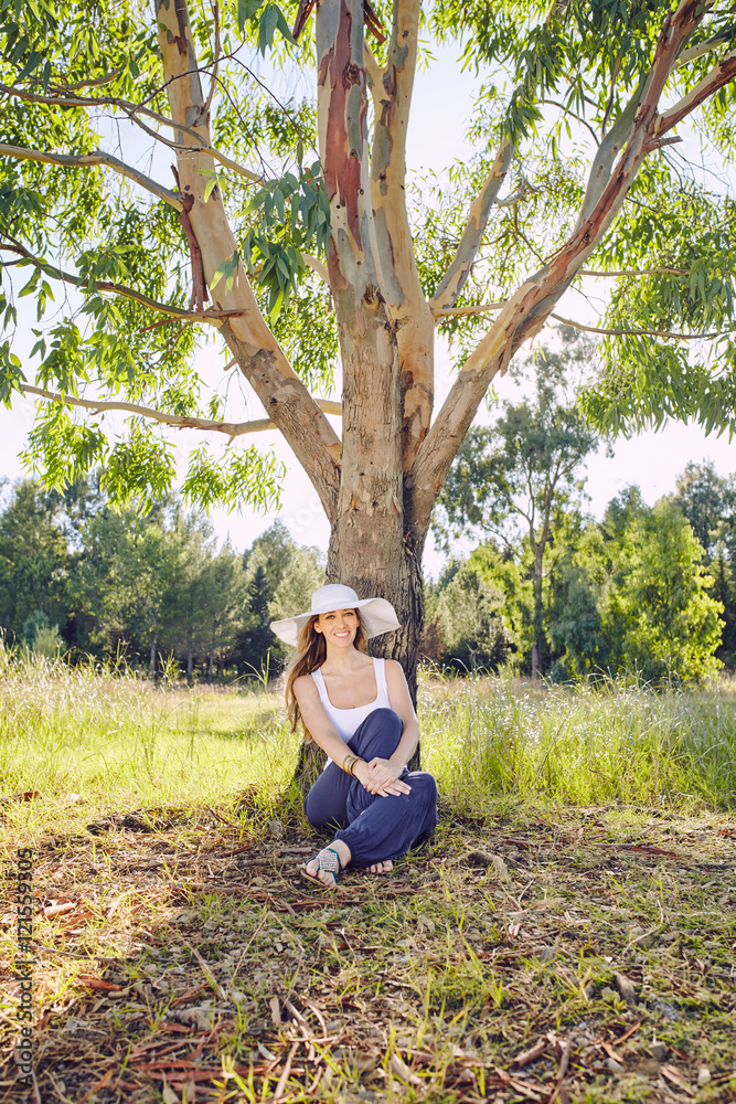 Blonde woman under a tree with a white hat Blonde woman under a tree with a white hat