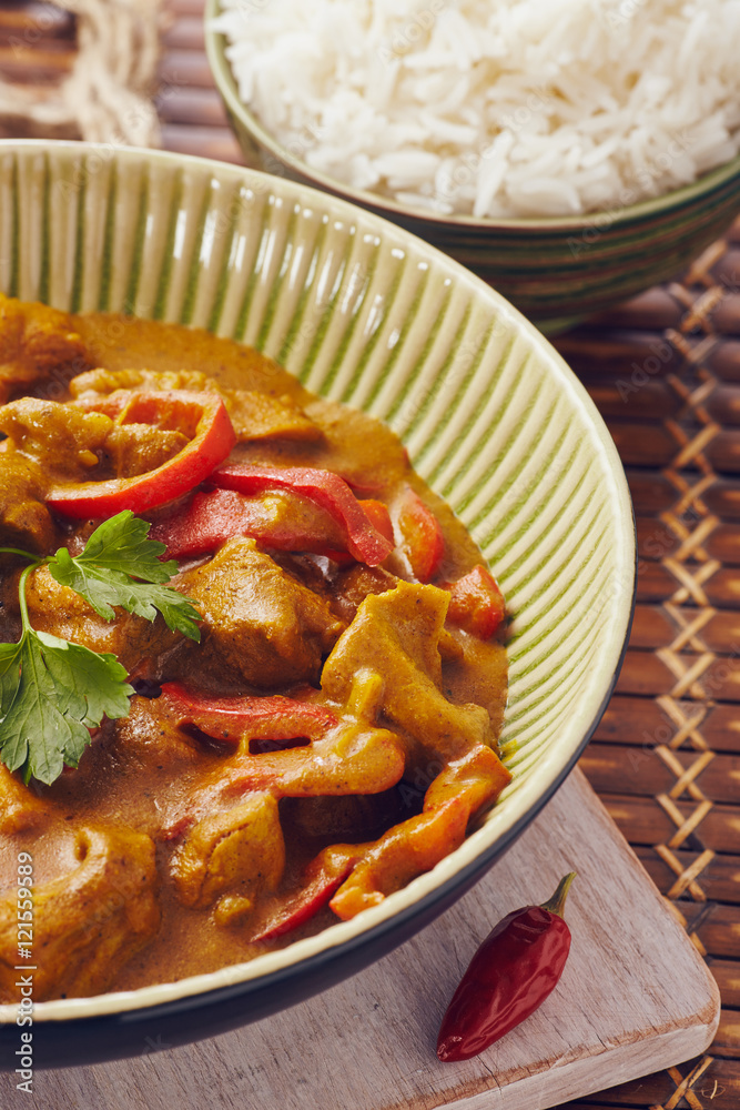 Curry chopped pork in a bowl with basmati rice on a bamboo placemat on a blue wooden table Curry chopped pork in a bowl with basmati rice on a bamboo placemat on a blue wooden table
