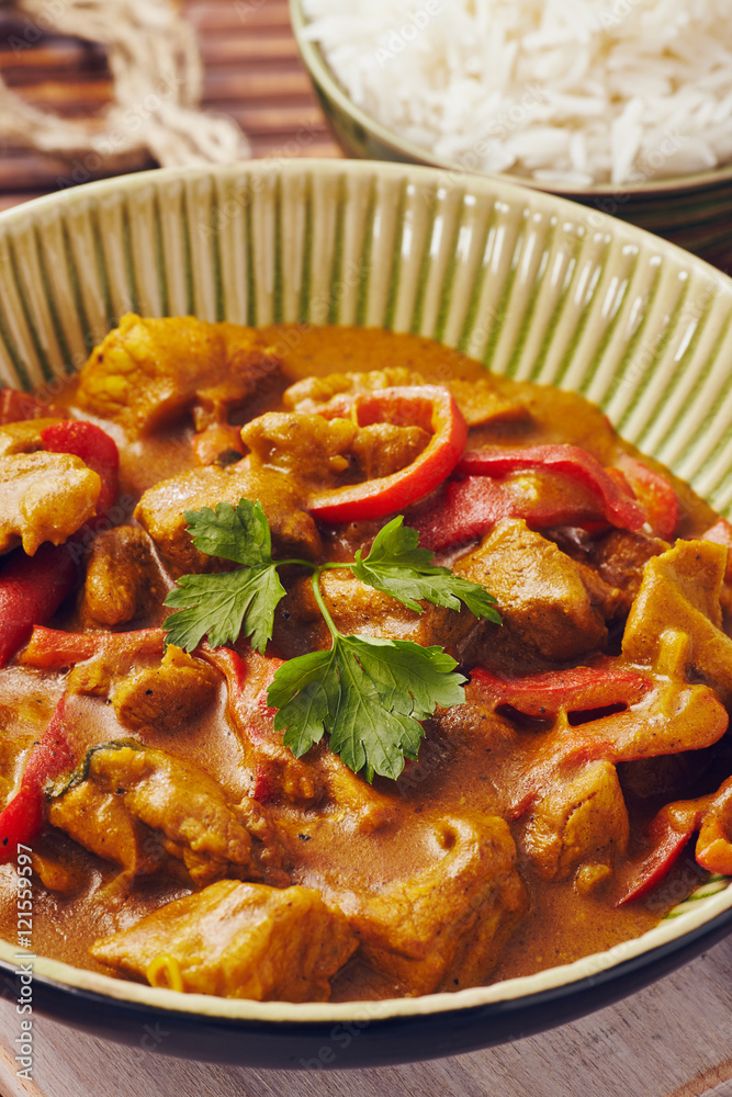 Curry chopped pork in a bowl with basmati rice on a bamboo placemat on a blue wooden table Curry chopped pork in a bowl with basmati rice on a bamboo placemat on a blue wooden table