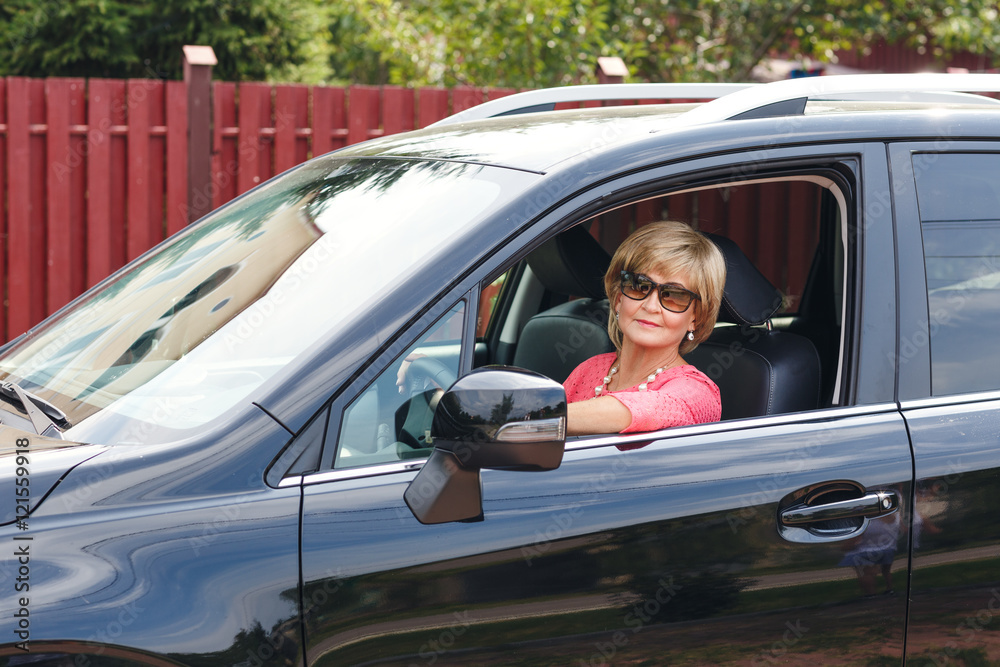 Portrait of attractive well-dressed senior woman driving a car Portrait of attractive well-dressed senior woman driving a car