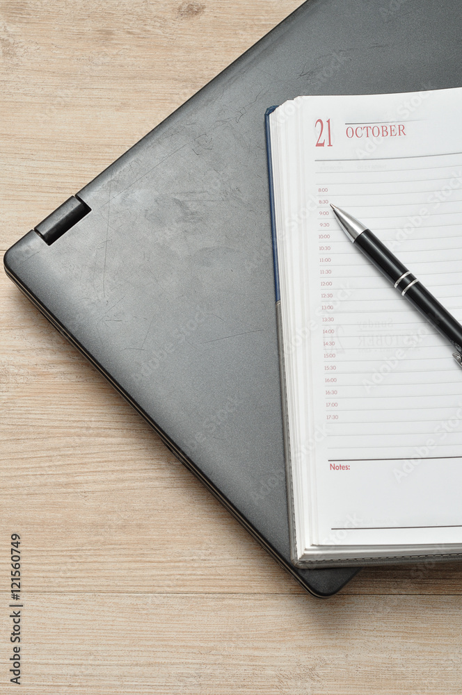 A laptop with a pen and an open diary A laptop with a pen and an open diary