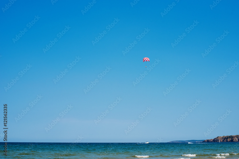 Parachuting over a sea, towing by a boat. Paragliding in the clear sky above the sea. Riding on a parachute behind a boat. Parachuting over a sea, towing by a boat. Paragliding in the clear sky above the sea. Riding on a parachute behind a boat.