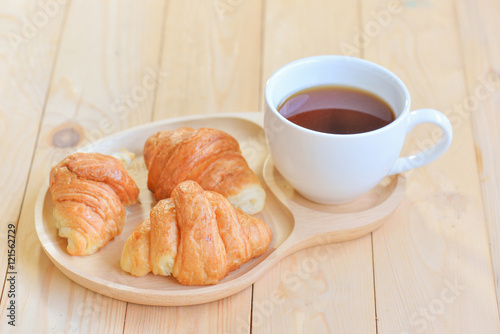 croissants with cup of coffee on wooden background