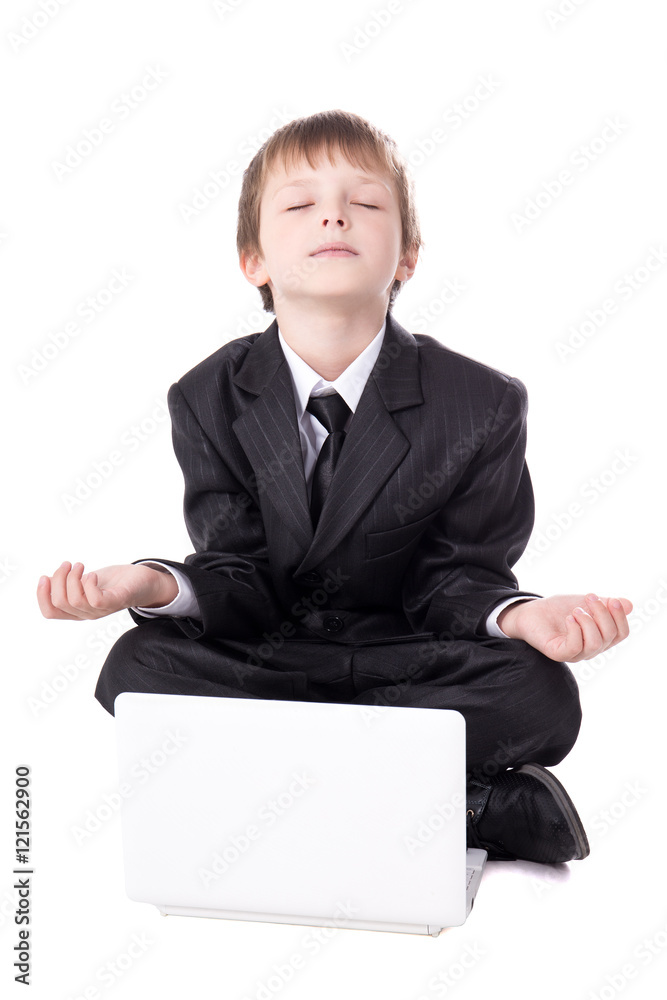 cute little boy in business suit sitting in yoga pose with lapto cute little boy in business suit sitting in yoga pose with lapto