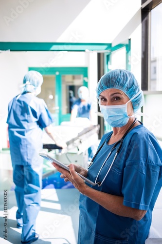 Surgeon using digital tablet in corridor © WavebreakmediaMicro