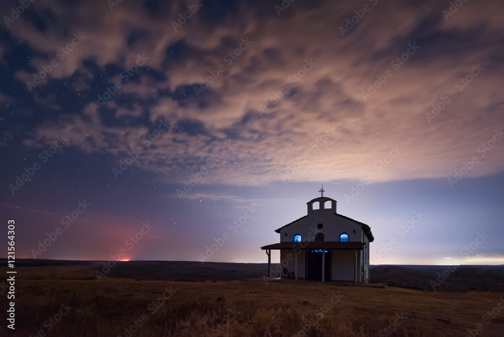 Starry cloudy night over the Chapel of St. George, Rusokastro village, Bulgaria 