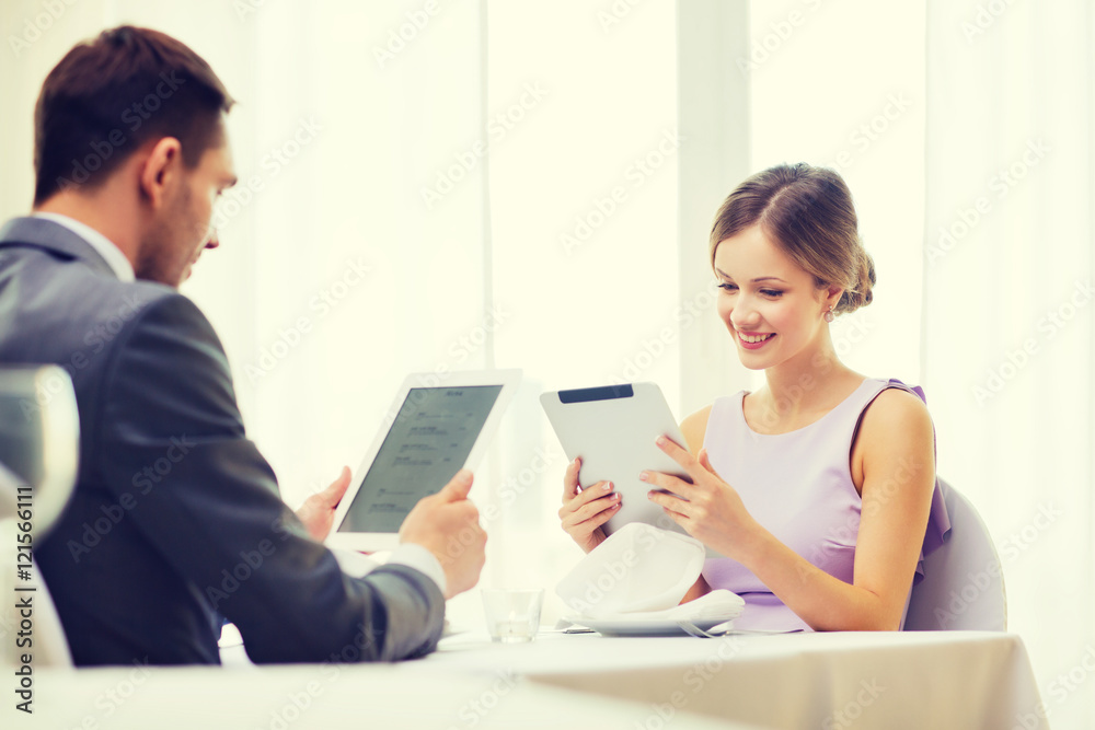 couple with menus on tablet pc at restaurant couple with menus on tablet pc at restaurant
