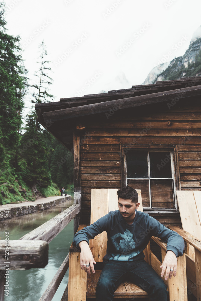 Man sit on a wood chair at braies lake Man sit on a wood chair at braies lake