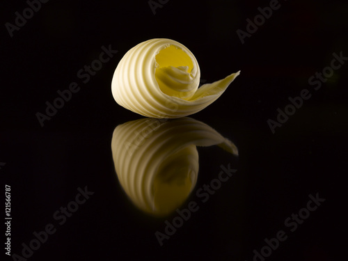 Butter slice on a black background. Reflection.