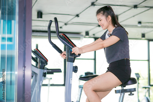 Beautiful fit asian woman exercising at the gym on bicycle
