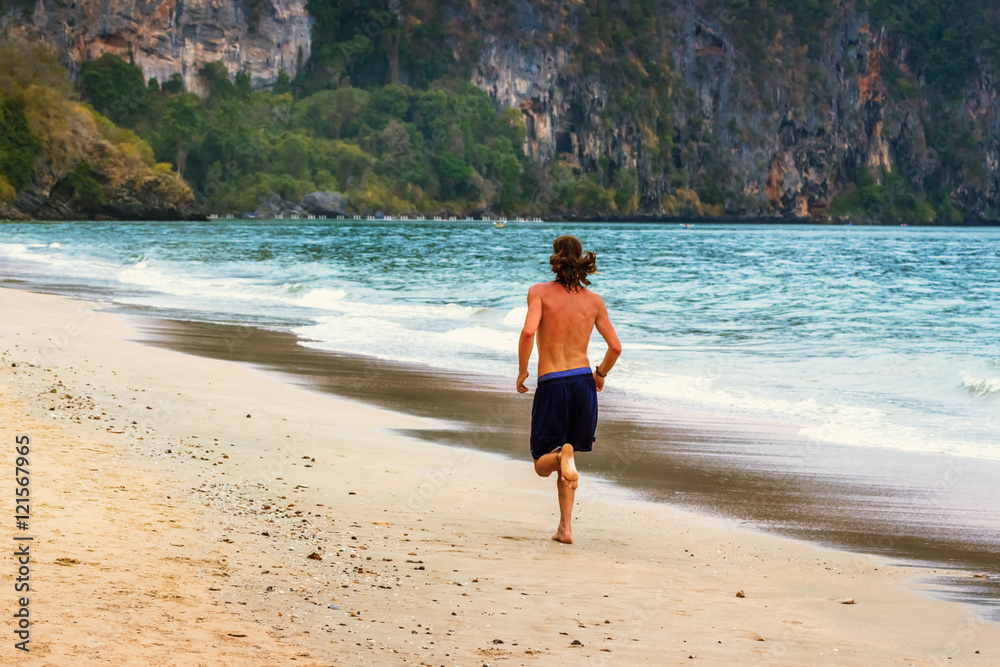 Young man jogging on the beach.